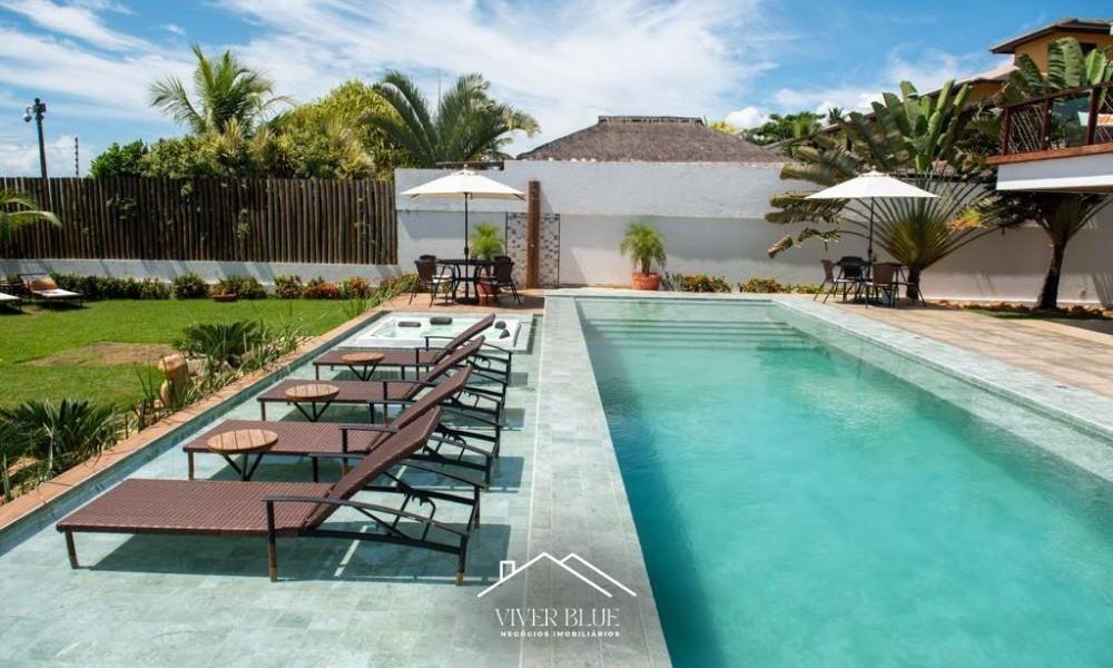 Casa de alto padrão frente mar em Arraial d’Ajuda, com piscina ampla, espreguiçadeiras e área externa sofisticada.