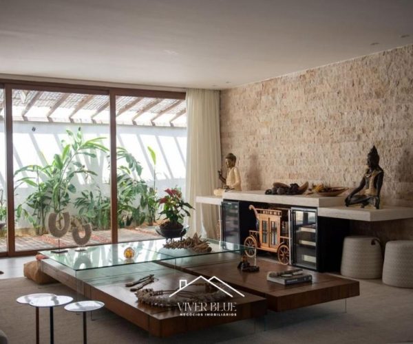 Sala de estar com parede em pedra, decoração sofisticada e ambiente integrado.