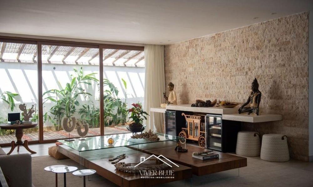 Sala de estar com parede em pedra, decoração sofisticada e ambiente integrado.