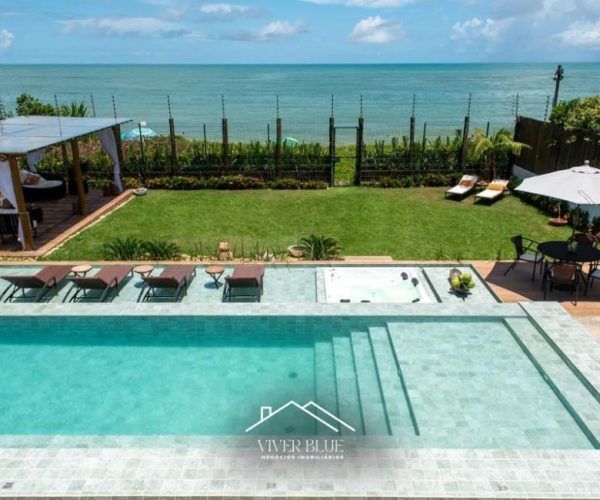 Área externa com piscina, jardim e vista para o mar, proporcionando lazer e contato com a natureza.