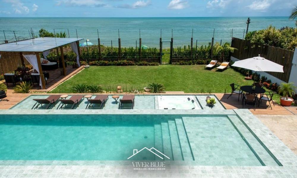 Área externa com piscina, jardim e vista para o mar, proporcionando lazer e contato com a natureza.